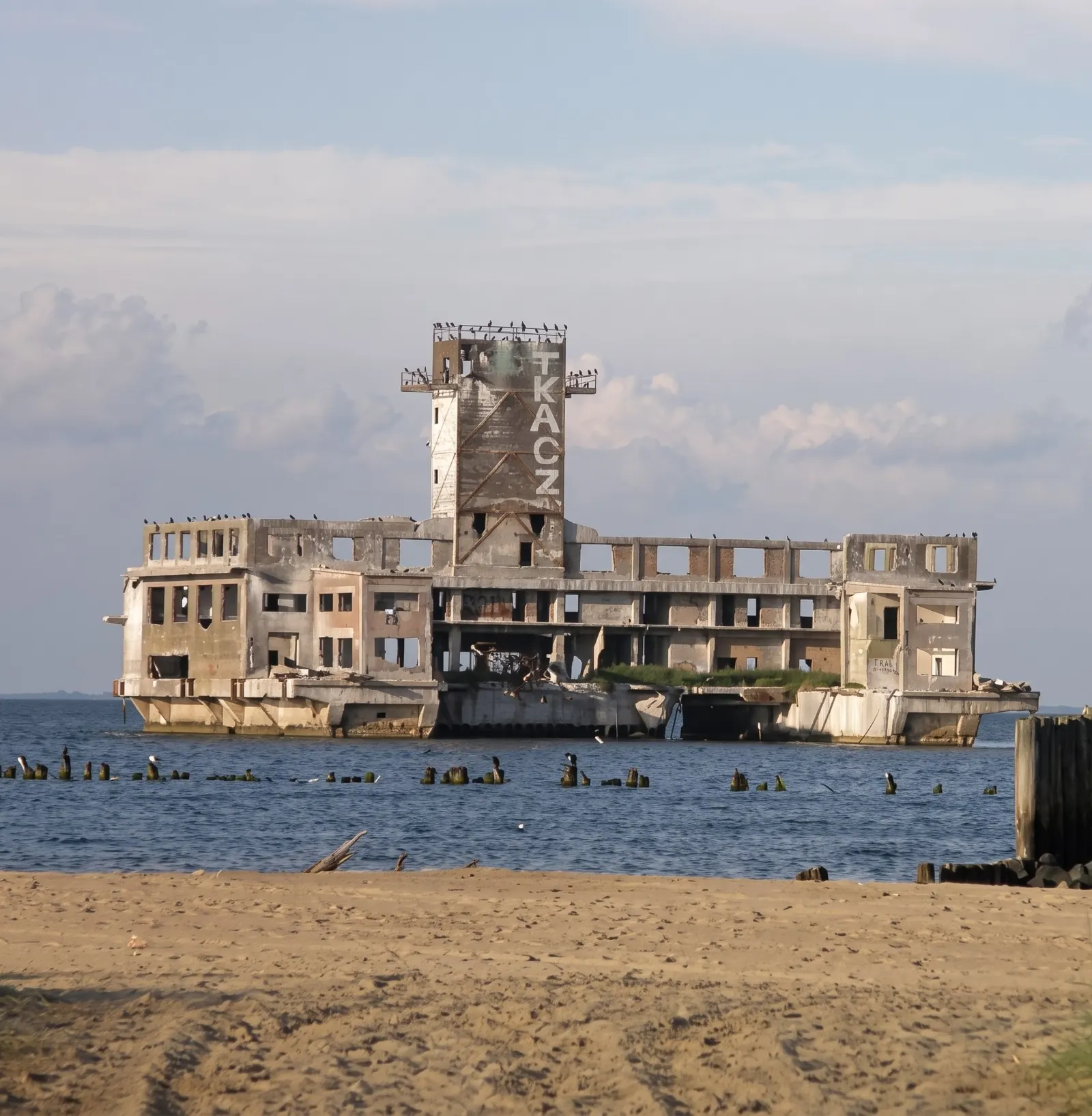 Ruina torpedowni widziana z plaży w Babich Dołach, przed nią rząd pali dawnego pomostu